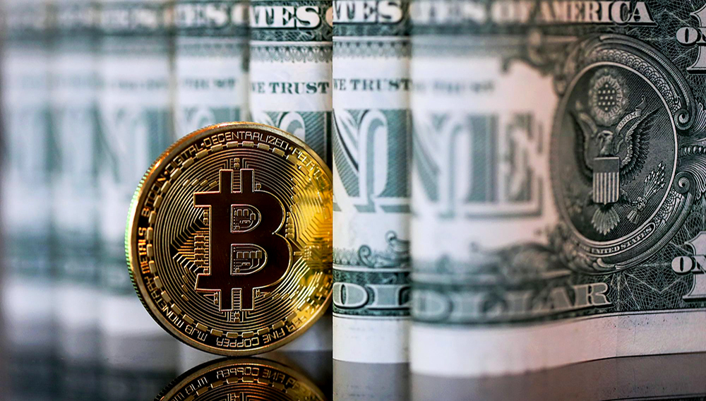 A bitcoin token stands next to a collection of U.S. one dollar bills in this arranged photograph in London, U.K. | PHOTO: Chris Ratcliffe/Bloomberg