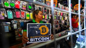 A vendor hods a sign reading "Bitcoin accepted" at a store in San Salvador, on January 26, 2022. (Photo by MARVIN RECINOS / AFP)
