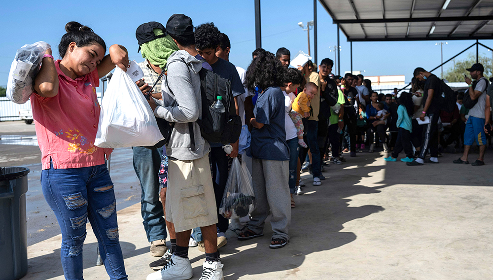 PHOTO: Migrants line up at Mission Border Hope in Eagle Pass, Tex., as they wait for a bus to Chicago in September. The nonprofit helps migrants after they are processed by U.S. Customs and Border Protection. (Andrew Caballero-Reynolds/AFP/Getty Images)