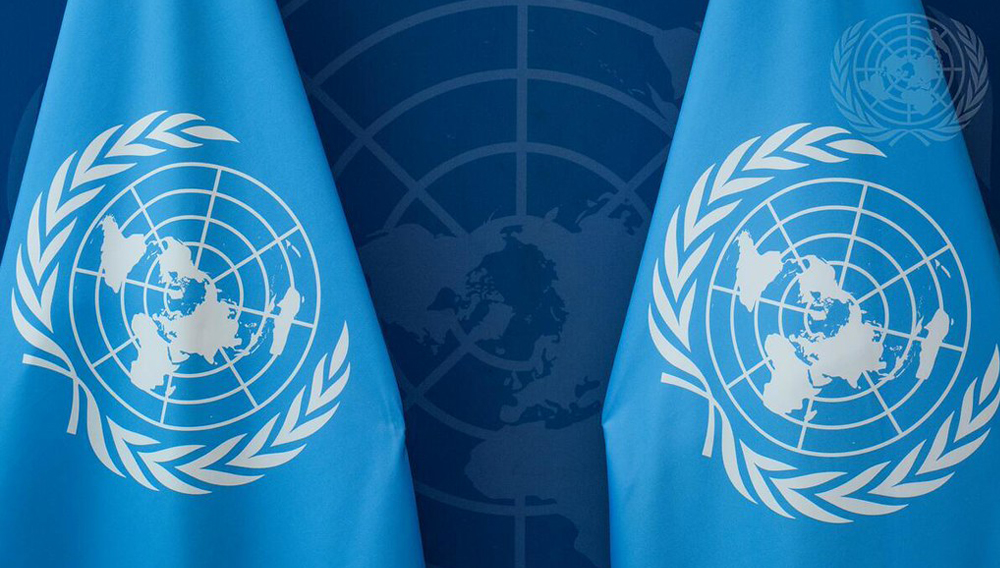 Two United Nations flags in front of a United Nations emblem on the wall behind. UN Photo/Manuel Elías. 29 September 2025. New York, United States of America.