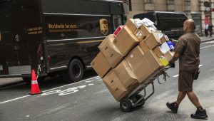 A driver for an independent contractor to United Parcel Service Inc. pushing a dolly of packages toward a delivery van in New York. Photo: Victor J. Blue/Bloomberg News