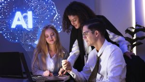 Photo: Multinational team of one man and two women gathered to brainstorm and discuss their work together. They used computers to present a stock market report using AI charts.