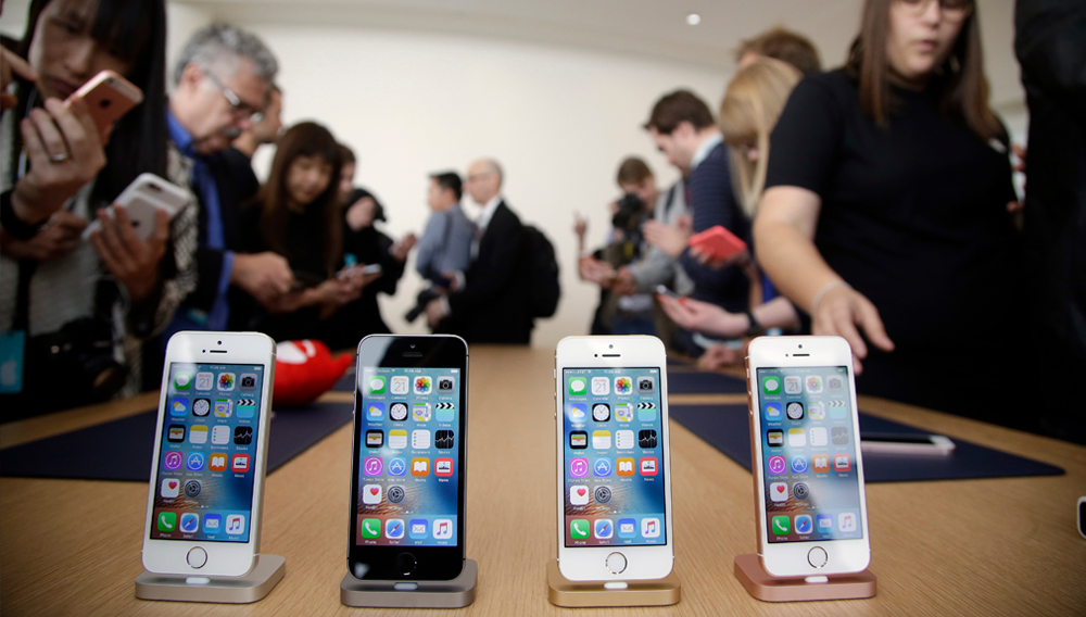In this March 21, 2016, file photo members of the media and invited guests take a look at the new iPhone SE during an event at Apple headquarters in Cupertino, Calif. (AP Photo/Marcio Jose Sanchez)