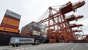 A truck carries a container near a cargo ship at the Port of Vancouver in Vancouver, British Columbia, Canada August 3, 2025. REUTERS/Chris Helgren
