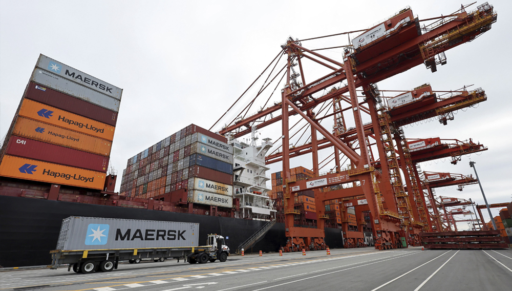 A truck carries a container near a cargo ship at the Port of Vancouver in Vancouver, British Columbia, Canada August 3, 2025. REUTERS/Chris Helgren